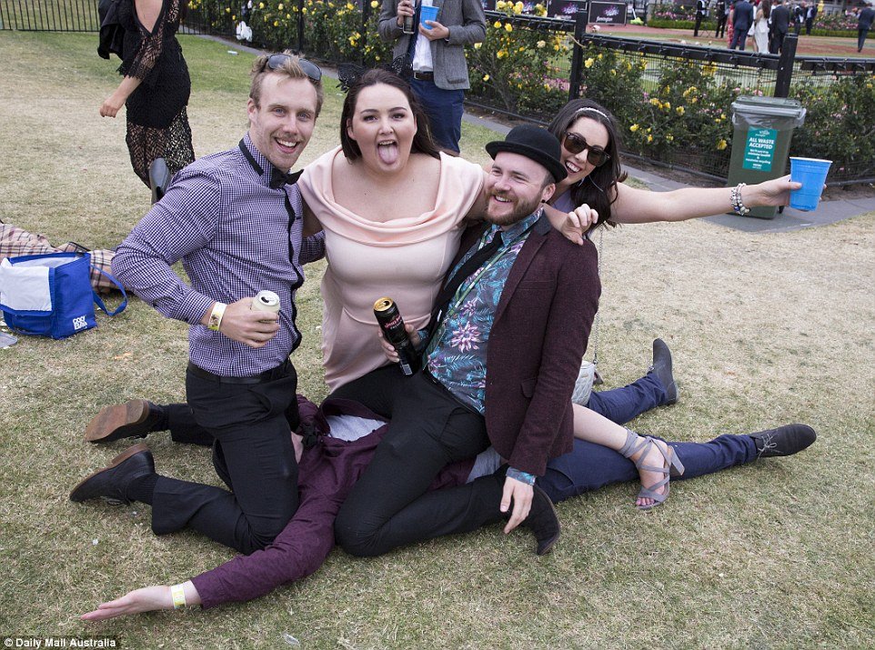 Linked arm-in-arm, this group pose together for a photo as they straddle a friend lying motionless on the ground 