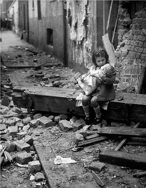 Маленькая девочка со своей куклой на руинах её дома в Лондоне. 1940 год