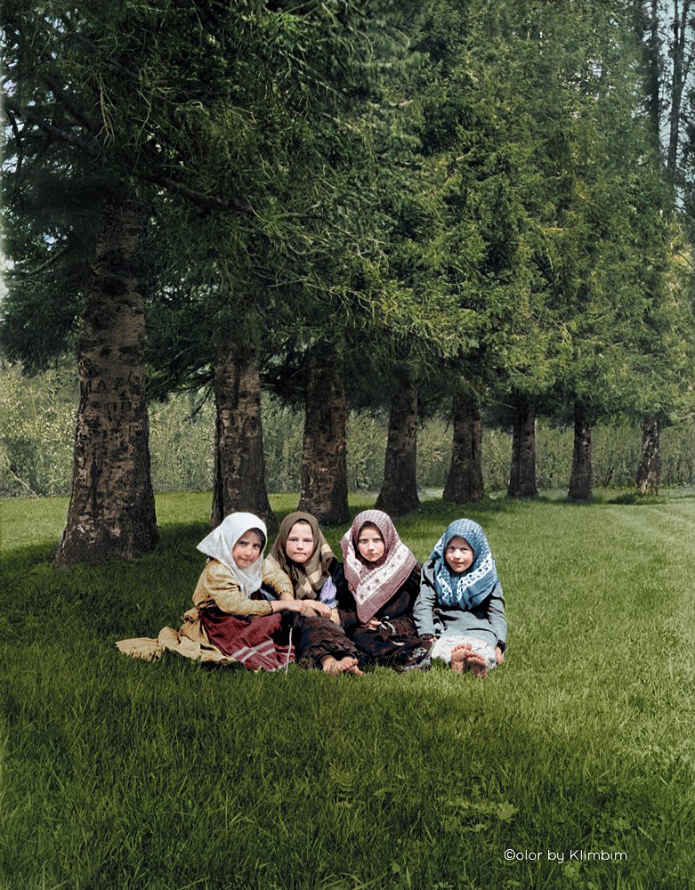 Four-young-girls-in-headscarves-sit-together-under-trees-on-grass,-Russia-1900s.jpg