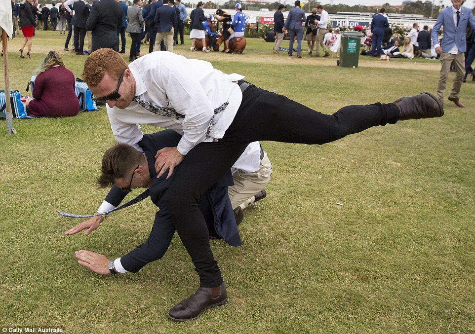 The two men are seen falling to the ground in a fight, just metres from other racegoers trying to enjoy their day 