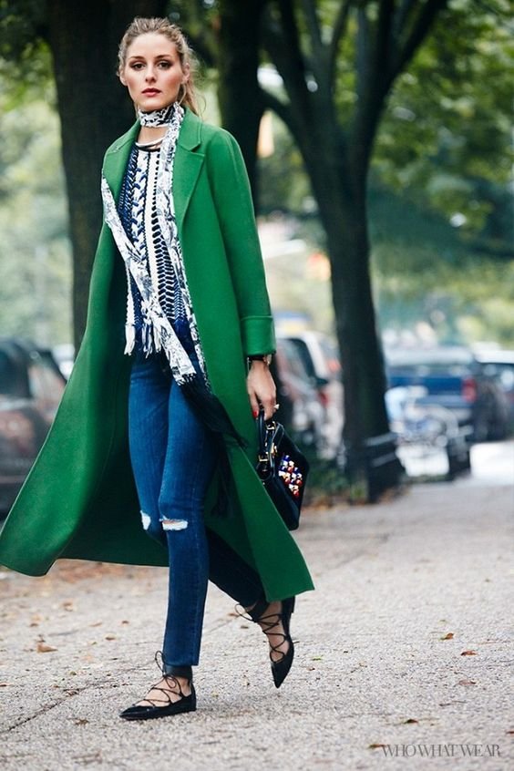 Olivia Palermo wears a green coat with a printed blouse, a skinny scarf, jeans, lace-up flats and a beaded handbag.: 