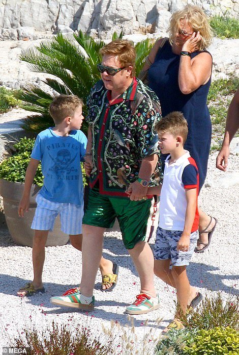 Doting dad: The Rocketman star commanded attention in a floral embroidered jacket and green shorts by Gucci as he held hands with his two sons Zachary, eight, and Elijah, six